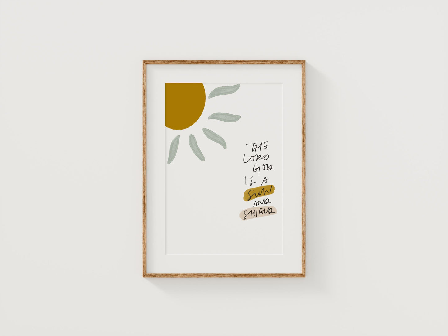 Handwritten Psalm 84:11 wall art reading “The Lord God is a sun and shield” with sun illustration in mustard yellow and sage green, styled in a wood frame on a white wall
